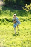 Little girl with a teddy bear on the meadow