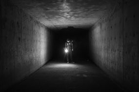 man with flashlight in the dark tunnel