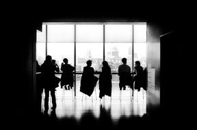 silhouettes of people on chairs near the window