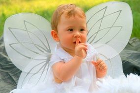 portrait of toddler in a white angel costume with wings