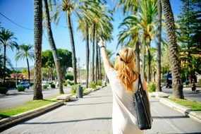 blonde wavy haired woman pointing to the sky
