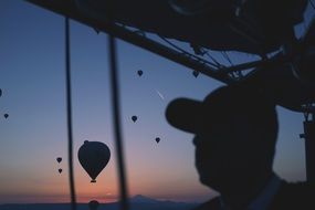 Photo of man at the background flying hot air balloons