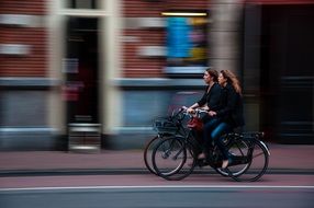 girls on bicycles ride down the street