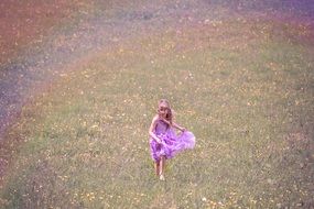 little girl in a pink dress runs on a clearing