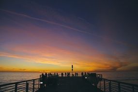 people on the pier at dusk at sunset