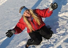 The girl is sitting on the snow and smiling