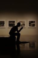 silhouette of man sitting in exhibition gallery