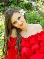 portrait of a girl in a red dress on a background of green grass