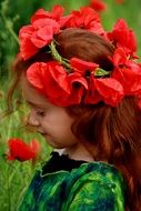 side view of a red-haired girl with poppies in her hair