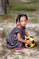 little girl with a soccer ball on the street