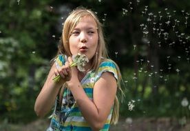 photo of the girl is blowing a dandelion