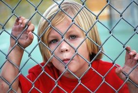 boy looking through the metal fence