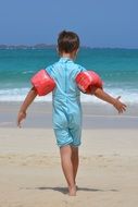 A boy on the beach with rubber rings in his hands