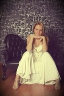 girl in a wedding dress sitting on a leather chair