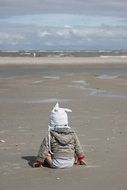 kid sitting on the beach of the north sea