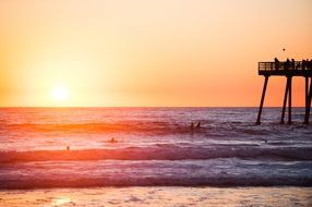 high pier in the ocean on a background of pink sunset