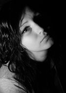 Monochrome portrait of a girl with dark hair in the dark