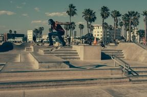 dark skin skateboarder jumping at urban landscape