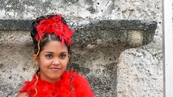 bright cuban girl near a stone wall