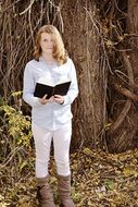 girl with a book in hands near a tree