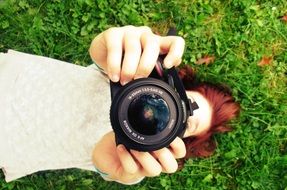 Lying on a grass girl holding a camera