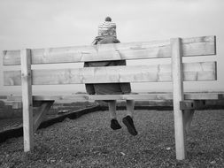 black and white picture of the child is sitting on a bench