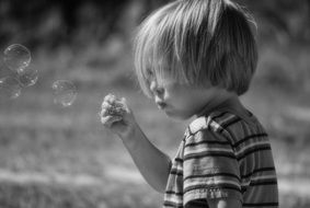 little boy is blowing soap bubbles