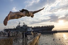 man jumps into the water from the tower