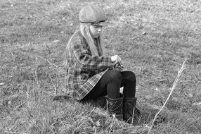 black and white photo of a girl sitting in a meadow