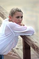 girl sits by the wooden fence