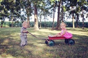 boy pulls a wagon with a girl