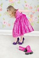 little girl puts on high-heeled shoes