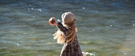 child throwing up a stone to the sea