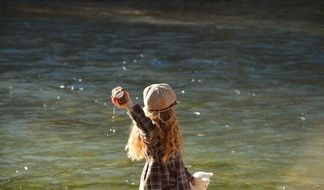 girl throwing stone into the water