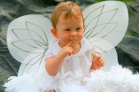 a toddler in a white angel costume with wings