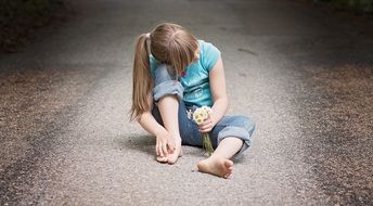 girl with a bouquet of daisies sits on the road