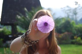 girl with a purple flower in the garden on a bright sunny day