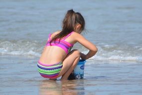 little girl is playing by the sea