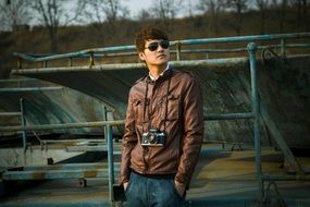 young man in a brown jacket and with a camera