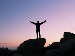 silhouette of the man is standing on a rock