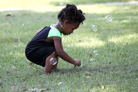 black girl plays with soap bubbles in the garden