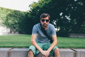 Seated man with glasses wearing shorts