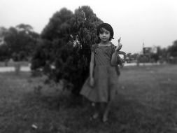 black and white photo of a girl near a bush