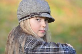 Blonde girl with grey cap looking back