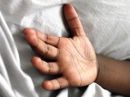 black baby hand on a white pillow