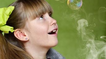 little girl looks at the soap bubble