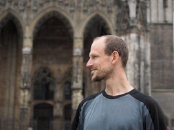 photo of a smiling man against the background of an antique cathedral