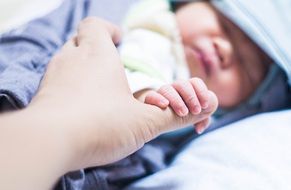 baby holds mum's finger