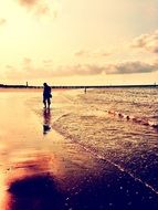 photo of the lonely man is walking on a beach at the sunset