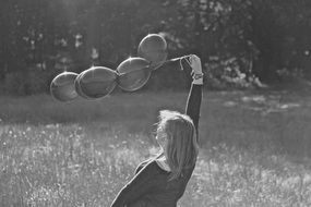 Black and white photo of girl playing with a balloons